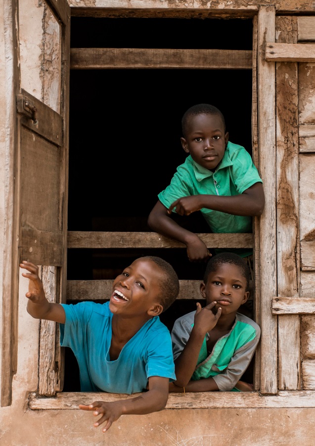 Happy orphans peeking from a window